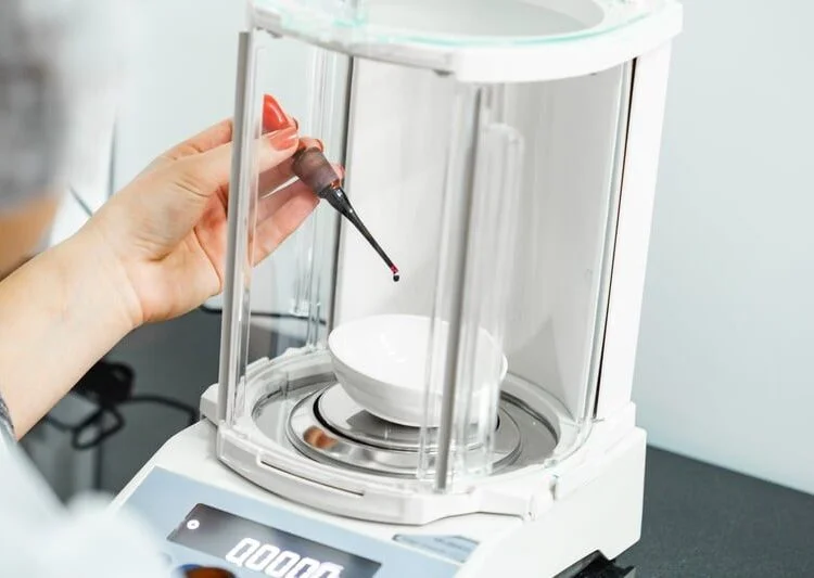 Analytical balance with a glass draft shield in a laboratory