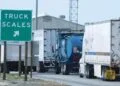Semi-trucks lined up at a highway weigh station where truck axle weight limits are checked