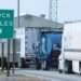Semi-trucks lined up at a highway weigh station where truck axle weight limits are checked
